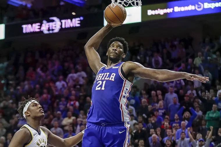 Sixers center Joel Embiid attempts to dunk the basketball against Indiana Pacers center Myles Turner.