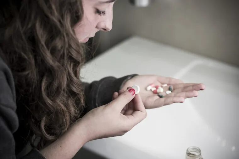 Teen girl holding a selection of pills