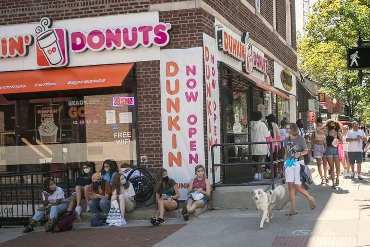 Students sit on their phones outside of a Dunkin Donuts in State College, PA on Saturday, Sept, 05, 2020.