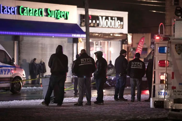 Investigators look over the area after New York City police officers were shot while responding to a robbery at a T-Mobile store in the Queens borough of New York on Tuesday, Feb. 12, 2019.