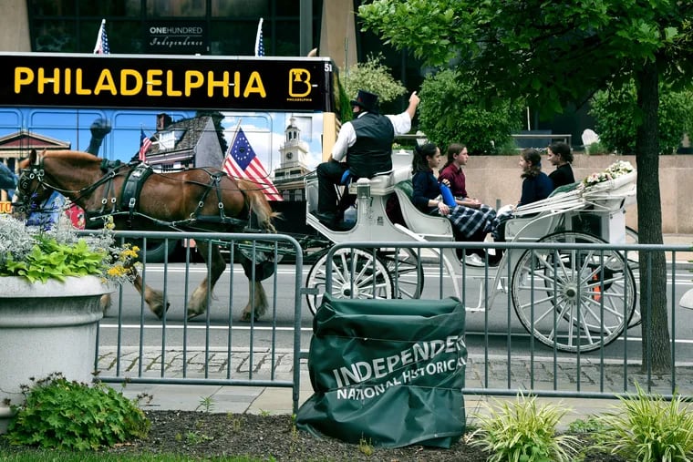 A tour guide points out historic sites from a tourist horse drawn carriage near Independence Mall in June.