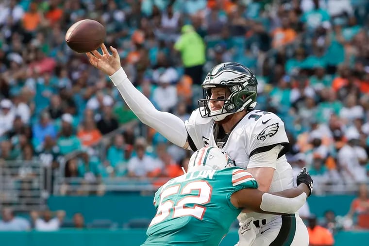 Eagles quarterback Carson Wentz gets rid of the football as he absorbs a hit from Dolphins linebacker Raekwon McMillan.