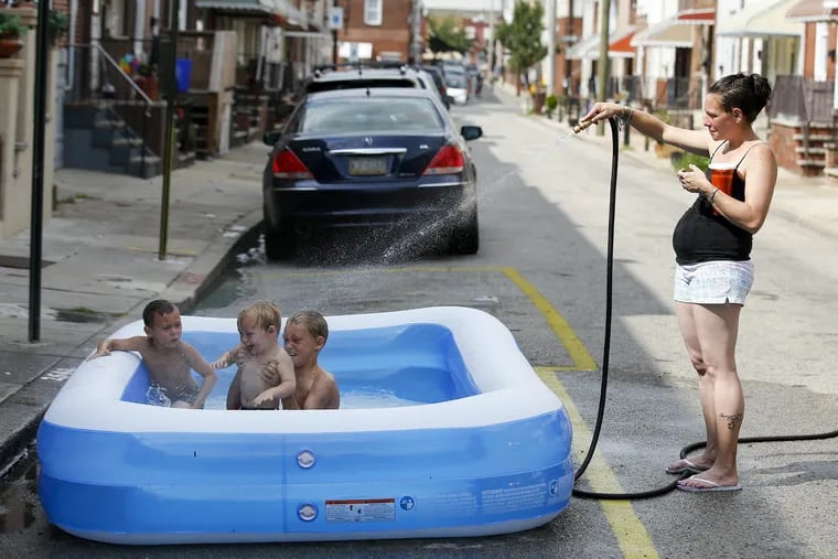 Mother Alexis Denaro spays water into a inflatable pool on her son's (right to left): Dominic Denaro, 8, William Giangrante, 5 and Lorenzo Giangrante, 2, on the 2500 block of Darien in South Philadelphia on Friday, July 21, 2017 in Philadelphia.