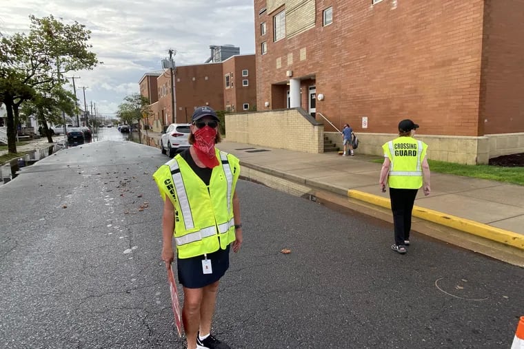 With a flooded street behind her, Margate, N.J. Crossing Guard Dawn Flynn stands outside the William H. Ross school on Thursday. She's seeing New York and Pennsylvania families dropping off kids this year at the Jersey Shore school.