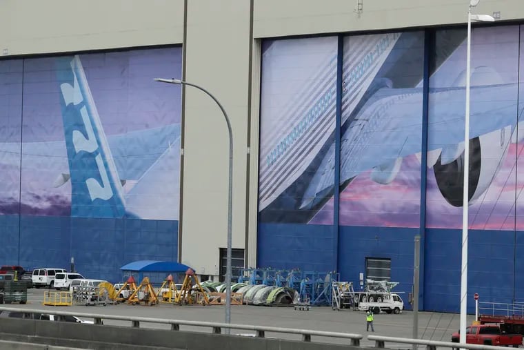 A worker walks near a mural of a Boeing 777 airplane at the company's manufacturing facility in Everett, Wash.
