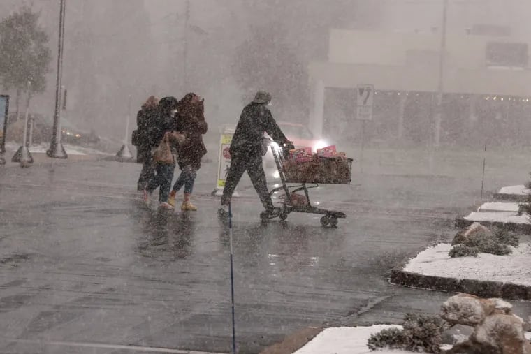 Shoppers at Wegman’s in Cherry Hill scurry in and out of the store during an intense snow squall on Monday. Several hit the region; one in Schuylkill County was deadly.
