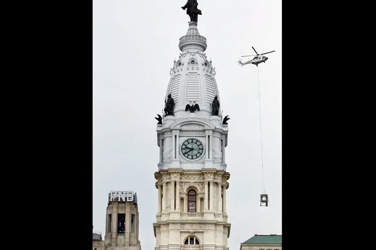 A helicopter lifts a P, the first letter removed from the south facing side of the PNB sign at 1 S. Broad St., and carries it past City Hall, August 17, 2014.