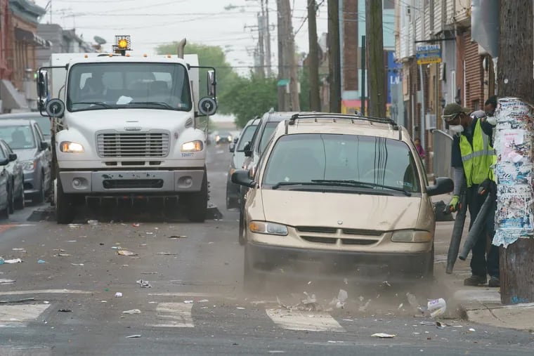 Street sweeping crews blow trash into the street to be picked up by a truck, on South 7th street, in Philadelphia, May 2, 2019. The pilot street cleaning program will continue through November, when the City will decide whether to continue and expand.