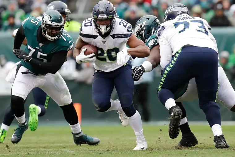 Seattle Seahawks running back Rashaad Penny runs with the football past Eagles defensive end Vinny Curry in 2019.