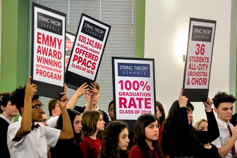 Students from the Philadelphia Performing Arts Charter School, a String Theory school, hold up signs in support of the proposed Joan Myers Brown Academy at Thursday's meeting. The board denied it, along with two other proposed charters.