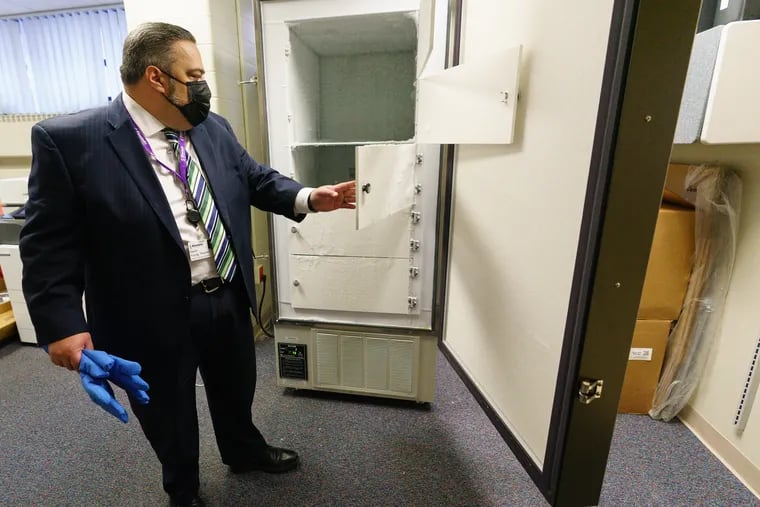 Pharmacy director David Young of Einstein Medical Center Philadelphia, is shown here with the ultra-cold freezer that Prizer's COVID-19 vaccine will be stored in. It is expected to arrive later this week. Young is holding special gloves that will protect worker's hands inside the freezer.  The vaccine must be stores at minus 94 F.