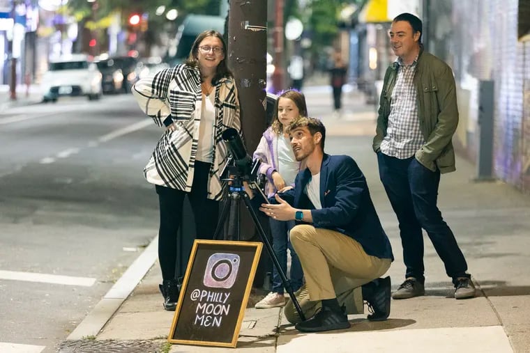 Brendan Happe (center) of the Philly Moon Men adjusts the telescope for Dahilia Franaszczuk so she can view Saturn from his telescope at Sixth and South Streets. Her parents, Emilia Andrezejewska and Mikolaj Franaszczuk, look on.