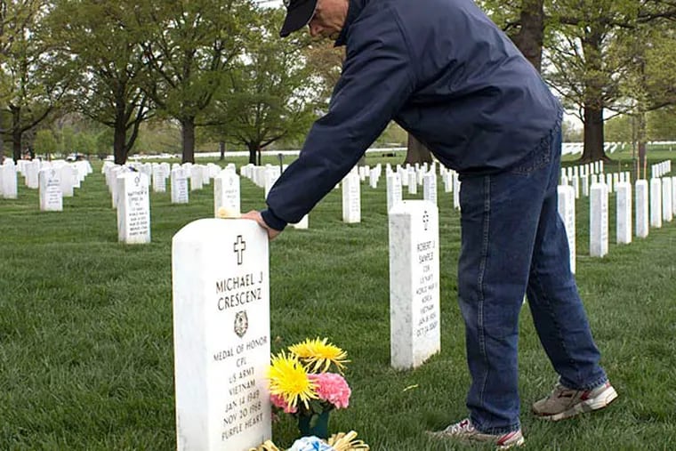 Joseph Crescenz touches his brother's headstone at Arlington National Cemetery. He remembers the day in 1970 he learned his brother, killed two years earlier, would be awarded the Medal of Honor. ROBERT MORAN / Staff