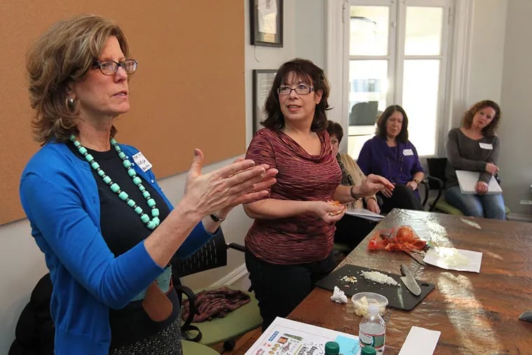 My Daughter's Kitchen program director Maureen Fitzgerald, left, talks to the volunteers who had gathered at Vetri Foundation for Children, to go over what to expect in the coming weeks of the program. Volunteer Andrian Seltzer, center, listens.