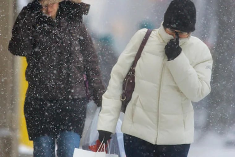 Sisters Lisa and Debbie Fisher of Havertown make their way through Sunday afternoon's snow at Suburban Square in Ardmore. (Ed Hille / Staff Photographer)