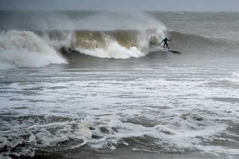 Arbey Vasquez surfs in the high waves in Ocean City on Tuesday. Fortunately the region escaped major flooding.