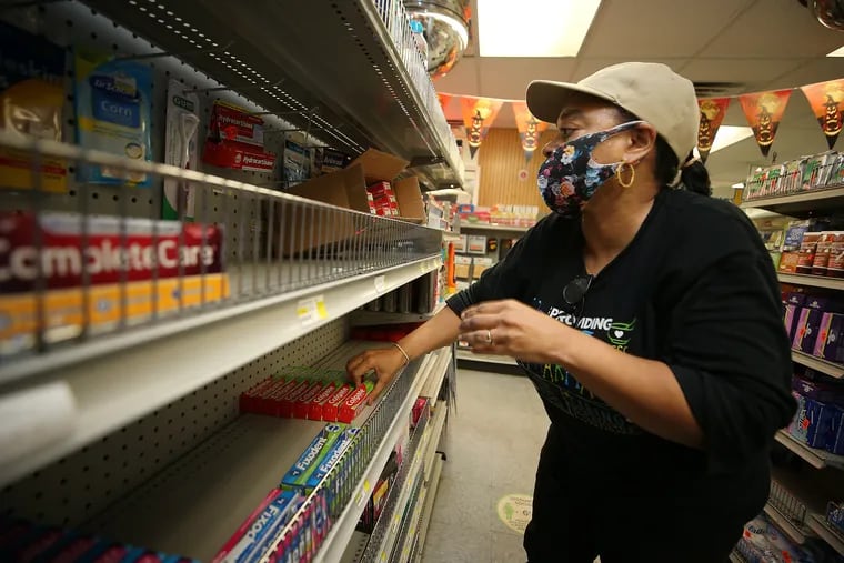 Tonjua Lyles, who has worked at Philadelphia Pharmacy for 29 years, restocks the shelves at the shop on Lehigh Avenue. More than 80 pharmacies have been looted around the city this week, including Richard Ost's shop, Philadelphia Pharmacy, in Kensington.
