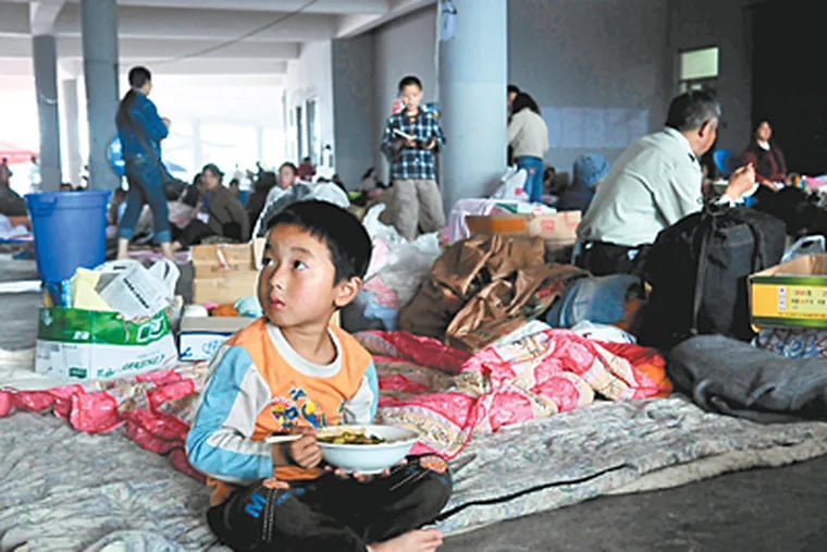A boy eats a meal delivered by Christian volunteers at the Jiuzhou sports gymnasium, the main center for help for displaced families. (Jennifer Lin / Inquirer)