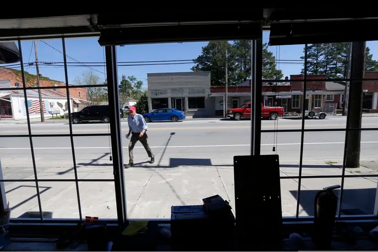 In this photo taken Wednesday, April 17, 2019 town manager Glenn Spivey crosses Jones Street in Trenton, N.C. Eight months after Hurricane Florence inundated North Carolina, communities such as Trenton illustrate the slow and uneven pace of recovery.