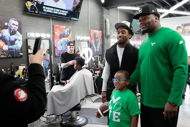 Eagles defensive tackle Milton Williams (right) and cornerback Zech McPhearson pose with 6-year-old Evan Goode, Jr. during a holiday party hosted by the NFL players at Creators Barber Studios with free haircuts and gifts for local youth.