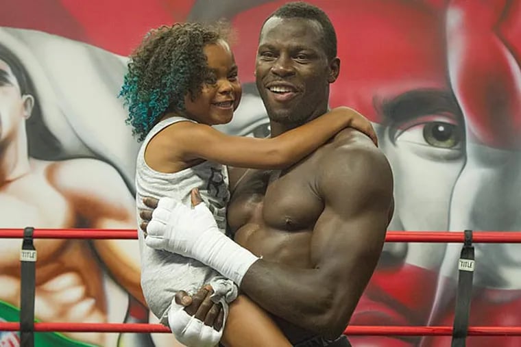 Philadelphia heavyweight boxer Steve Cunningham holds his nine-year-old daughter Kennedy in the ring at DSG Boxing Gym. (Clem Murray/Staff Photographer)
