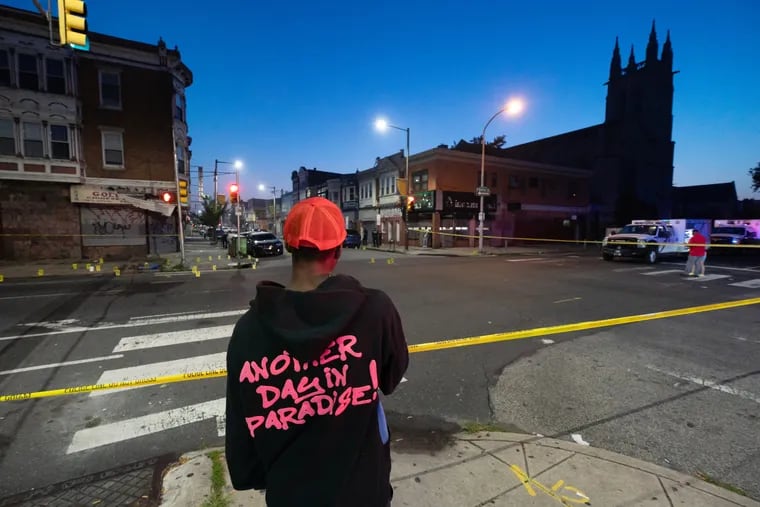 Kiko Hall, a friend of Sircarr Johnson Jr., stands at the crime scene at 60th and Walnut Streets, just as the sun was about to rise, he is wearing a hat and sweatshirt designed by Johnson, July 5th, 2021. Sircarr Johnson Jr., 23, was killed in a triple shooting at a July 4th cookout he had at his store Sunday night. Salahaldin Mahmoud, 22, was also killed, and a 16-year-old girl was injured by the gunfire.
