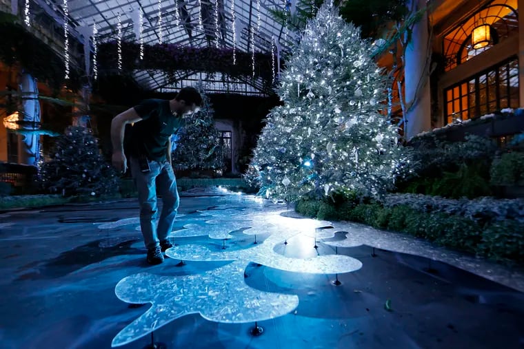 In the Exhibition Hall, Alpine Wonderland designer Kevin Bielicki adjusts carved acrylic pieces that mimic ice during A Longwood Christmas at Longwood Gardens.