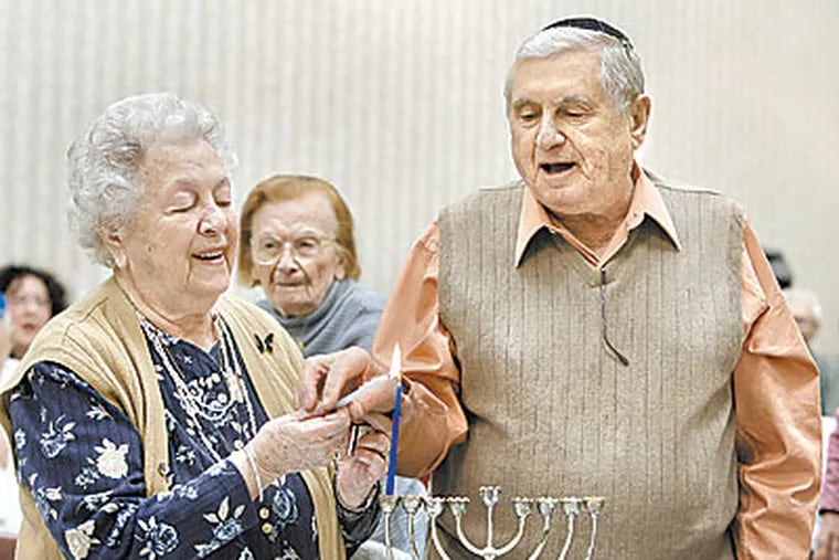 Lili and Emil Paul from Marlton, NJ light a hanukkah candle. Both are Holocaust survivors. (Akira Suwa / StaffPhotographer )
