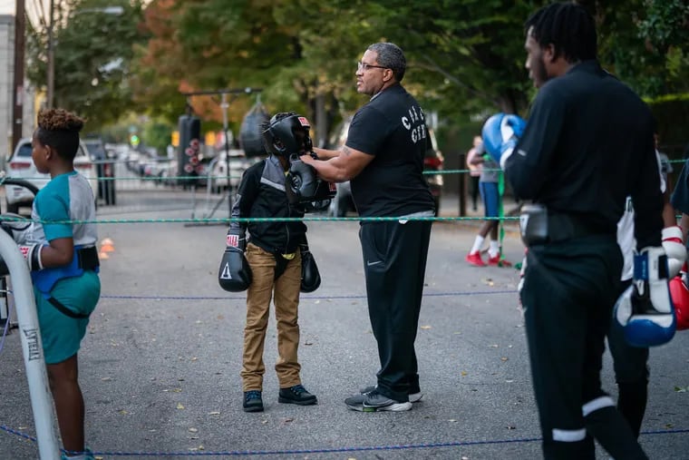 Officer George Gee works with participants in the boxing program Guns Down Gloves Up at the 22nd District in Philadelphia in October 2022.