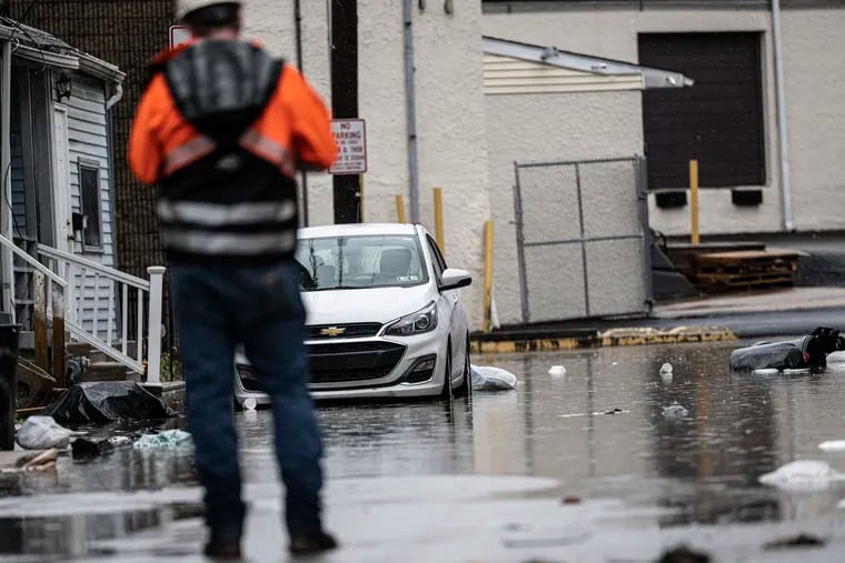 A worker assess the flooding damage on Florence Avenue near the Darby Creek in Collingdale in December, an especially rainy month in the region.