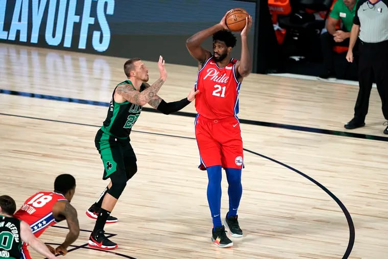 Boston Celtics' Daniel Theis, left, defends against Sixers center Joel Embiid (21) during the first half on Monday.