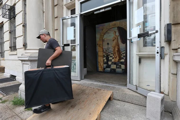 John Marino, of Broad Street Movers, carries items out of art studios at 915 Spring Garden St. A fire last week at the building led to inspections by the Department of Licenses and Inspections, which found numerous violations. (DAVID MAIALETTI/Staff Photographer)