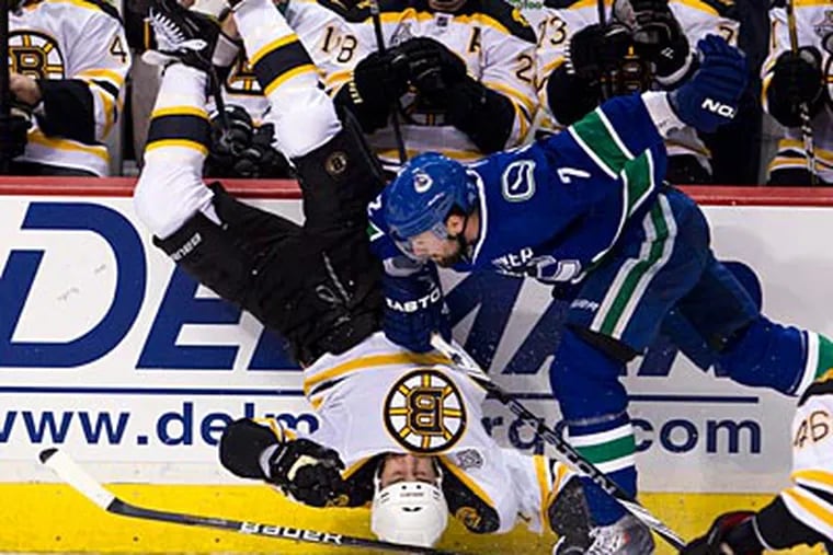 The Bruins' Milan Lucic is upended by the Canucks' Dan Hamhui. (AP Photo/The Canadian Press, Jonathan Hayward)