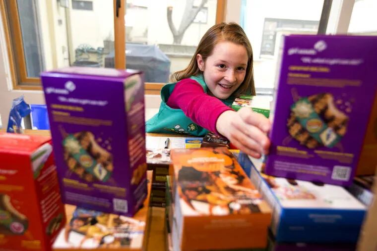 Girl Scout Willa Weidner, 9,  reaches for a box of Girl Scout cookies as she gets an order together for delivery. Mom Christie Weidner posted cookie information on her private Facebook group of 63 current and former neighbors. But the family prefers the traditional door-to-door selling method.