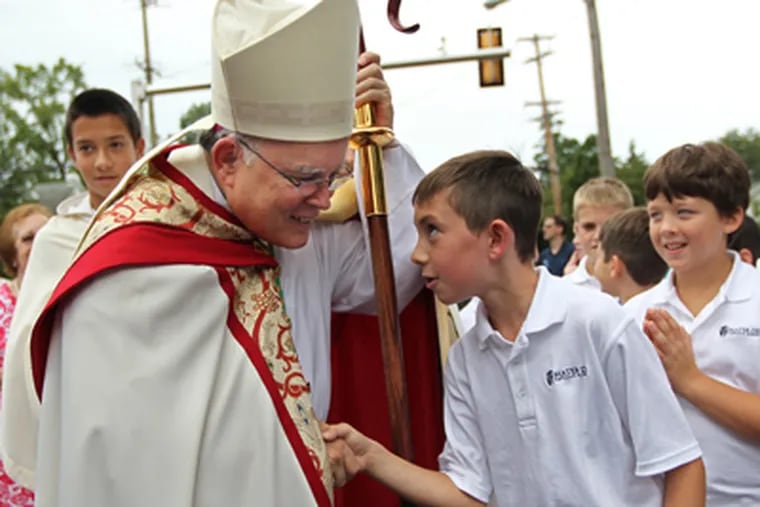 Gabriel Collier, 10, right, a 5th grader at the new Mater Dei Catholic School in Lansdale, shares a quick moment with Archbishop Charles Chaput as Chaput mingled with the students before blessing the new school. MICHAEL BRYANT / Staff Photographer