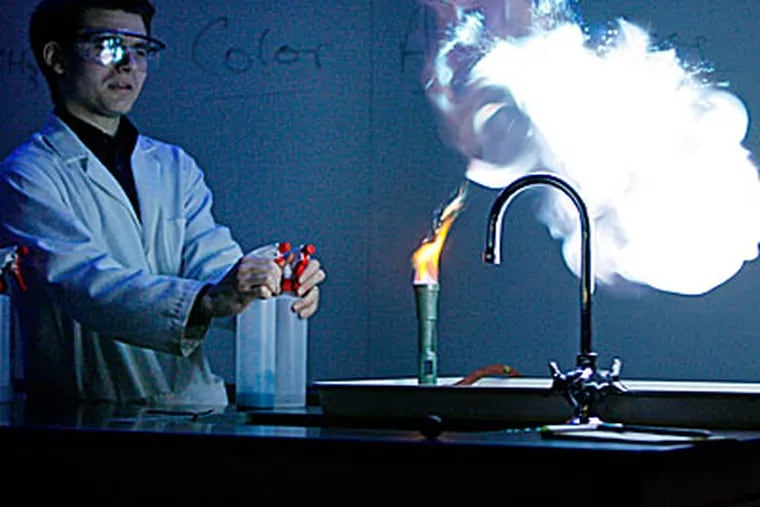 Mike Rheam, a demonstration coordinator in the chemistry department, shows how heavy-metal atoms produce colors in the heat of a flame. (MICHAEL S. WIRTZ / Staff Photographer)