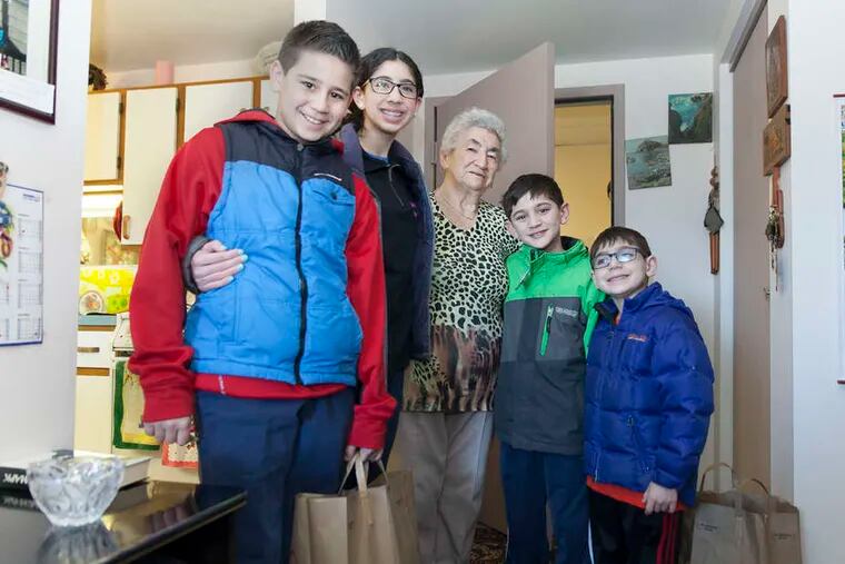 At the Robert Saligman House, resident Feyga Karp (center) stands with Project HOPE volunteers (from left) Emmett, Talia, Max, and Joel Kepniss after delivery of her Passover box.