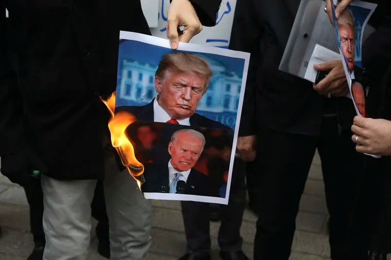 A group of protesters burn pictures of U.S. President Donald Trump and President-elect Joe Biden in a gathering in front of Iranian Foreign Ministry on Saturday.