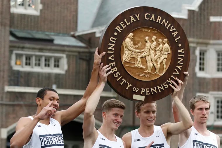 A Penn State relay team at the 2016 Penn Relays holds up the historic wheel  awarded to victors.