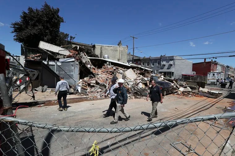 Investigators examine the remains of the collapsed three-story building along the 300 block of West Indiana Avenue in the Fairhill section of Philadelphia on Sunday, one day after a firefighter died and four others, along with a city building inspector, were injured in the post-fire collapse.