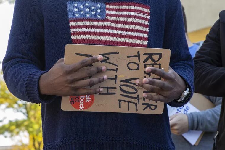 Khalil Bryant holds a clipboard as he encourages students to pledge to vote on Election Day.