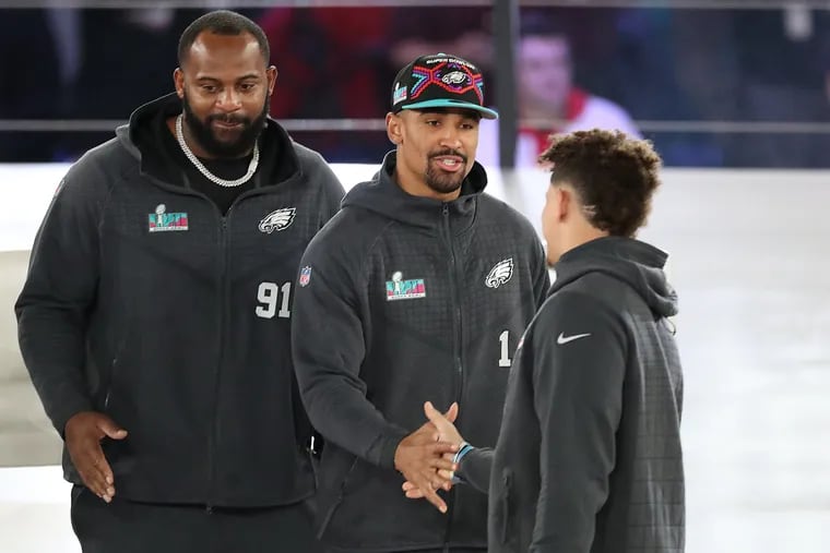 Philadelphia Eagles quarterback Jalen Hurts (center) and Kansas City Chiefs quarterback Patrick Mahomes (right) shake hands during the Super Bowl LVII Opening Night event at the Footprint Center on Monday in Phoenix, Ariz.  Philadelphia Eagles defensive tackle Fletcher Cox (left) waits to greet Mahomes.