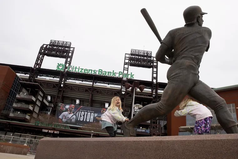 Ashley Talnack, 4, and Aubrey Talnack, 6, both of Chester Springs, pose near the Mike Schmidt statue at Citizens Bank Park on Wednesday, March 27, 2024.