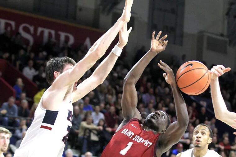 Shavar Newkirk, center, of St. Josephâ€™s gets stripped of the ball as he drives the lane against Penn during the 1st half at the Palestra on Jan 27, 2018. AJ Brodeur is left. CHARLES FOX / Staff Photographer