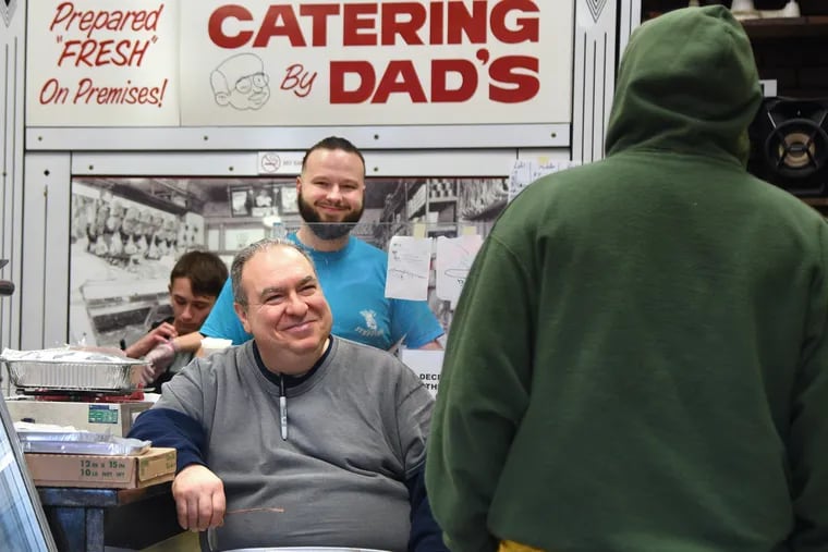 Carmen Commoroto Jr. (seated) and his son, Carmen Commoroto III, talk to customers at Dad's Stuffings. The fourth-generation corner shop and butcher on Ritner Street is home to a famous chicken meatball. The family has been making 30,000 of them in the days before Christmas.