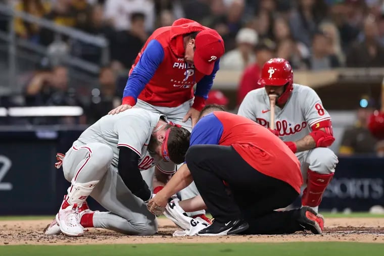 Bryce Harper is examined at the plate after he was struck in the thumb by a pitch on Saturday.