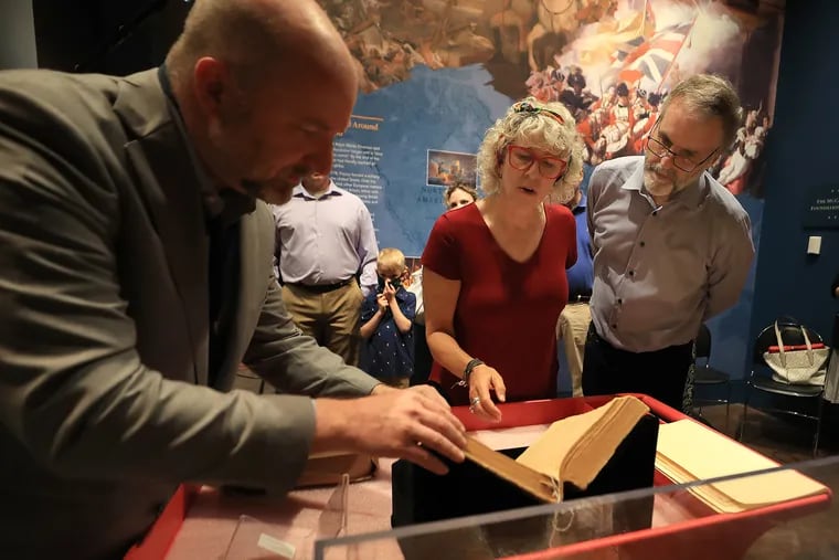 Chief historian and curator Philip Mead (left) of the Museum of the American Revolution, looks over the Claypoole family Bible with Aileen and David Edge inside the museum. The Edges’ donated the Bible to the museum.