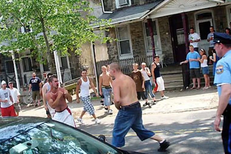 Two men duke it out in the middle of Manayunk Avenue at the end of the bike race on June 8, 2008, as a police officer prepares to break up the fight. Residents have cited similar problems at the event in recent years. (Vance Lehmkuhl / Philly.com)