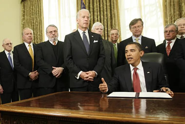 President Barack Obama, accompanied by Vice President Joe Biden, and retired military members, gets ready to sign an executive order in the Oval Office of the White House in Washington, Thursday, Jan. 22, 2009, closing the prison at Guantanamo Bay. (AP Photo/Charles Dharapak)
