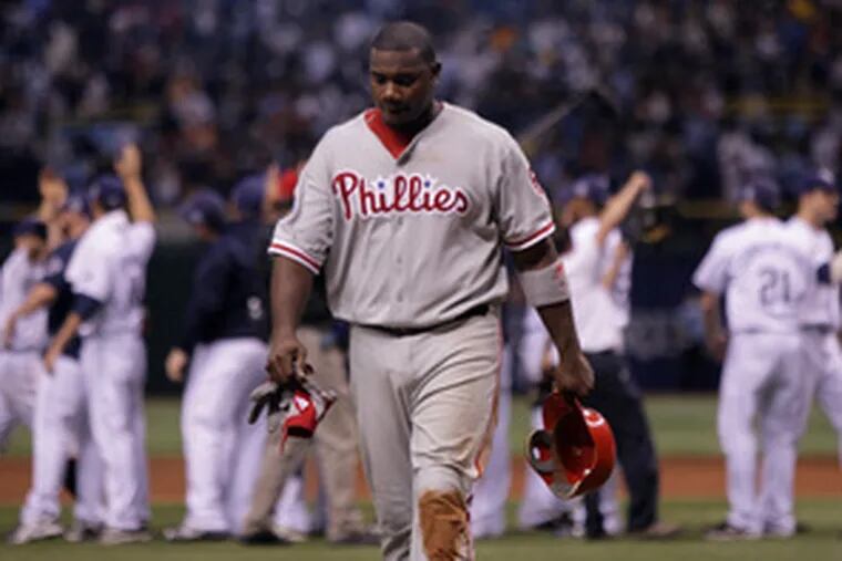 Ryan Howard dejectedly walks off the field after making the final out in the ninth, while Rays celebrate in background.